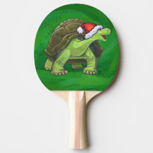 Tortoise in der Weihnachtsmannmütze auf grün Tischtennis Schläger