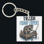 Trash Fishin' Expert Raccoon Schlüsselanhänger<br><div class="desc">Are you a fan of raccoons and fishing? This funny 'Trash Fishin' Expert' design features a master raccoon angler on a wooden dock with his gear. Perfect for anyone who loves trash panda memes, outdoor fishing trips, and a good laugh. This vintage-style illustration is a great gift for fishers, outdoorsmen,...</div>