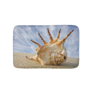 Tritonshorn-Muschel auf Sandy-Strand, blauer Badematte