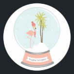Tropical Island Flamingo Christmas - Pink Runder Aufkleber<br><div class="desc">Ein Winter-/Weihnachtsaufkleber mit einer Illustration eines rosa Flamingo in einer Schneeglobe. Flamingo trägt einen rot gestreiften Schal und Hut,  während er auf einer schneebedeckten Insel mit zwei Palmen steht. Die rosa Basis sagt: "WARM WISHES."</div>