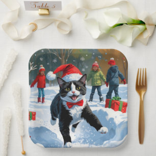 Tuxedo Katze läuft im Schnee mit Weihnachtsmütze Pappteller