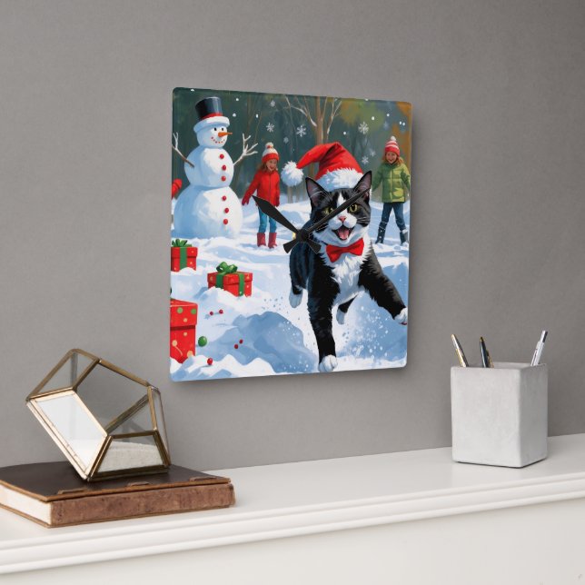 Tuxedo Katze läuft im Schnee mit Weihnachtsmütze Quadratische Wanduhr (Büro)