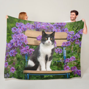 Tuxedo Katze sitzt auf einem Gartenstuhl mit Blume Fleecedecke