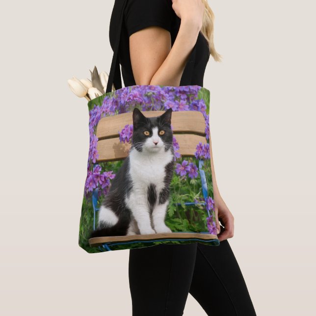 Tuxedo Katze sitzt auf einem Gartenstuhl mit Blume Tasche (Von Nahem)