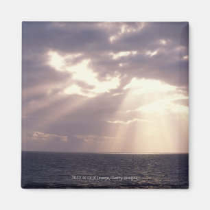 Untergehende Sonne, die durch Wolken über Ozean Magnet