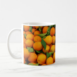 Viele farbenfrohe Orangen mit grünen Blätter Kaffeetasse