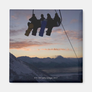 Vier Snowboarder werden auf einem Skiaufzug Magnet
