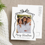 Vintag Black Bow Frohe Weihnachts-Foto Feiertagspostkarte<br><div class="desc">Feiern Sie die Urlaubssaison mit dieser bezaubernden Weihnachtspostkarte mit dem Foto Ihrer Familie, gerahmt von einem festlichen schwarzen Bogen und Band auf einem knusprigen weißen Hintergrund. "Frohe Weihnachten" ist elegant geschrieben in einem charmanten schwarzen handgeschriebenen Drehbuch, mit Platz, um Ihren Familiennamen unten zu personalisieren. Auf der Rückseite der Postkarte wird...</div>