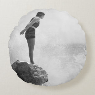Weibliche Schwimmerin auf Felsen über tosenden Wel Rundes Kissen