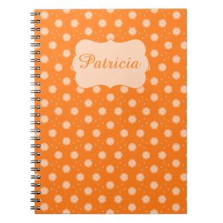 Weiche pfirsichfarbene-beige Blumen auf orangefarb Notizblock