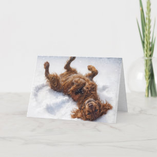 Weihnachts-Irish Setter macht einen Schneengel Feiertagskarte