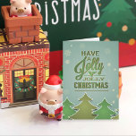 Weihnachtsbäume im Grünbuch Feiertagskarte<br><div class="desc">Weihnachtsbäume aus Papier in Grüntönen,  in Weiß umrissen. Schneeflocken scheinen einen blau grünen,  texturierten Hintergrund herunterzufallen. Grüne Typografie mit Heiliger.</div>