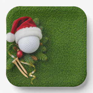 Weihnachtsgolfball trägt Santa-Hut auf grünem Rase Pappteller