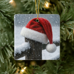 Weihnachtsmannmütze auf einem schneebedeckten Zaun Keramikornament