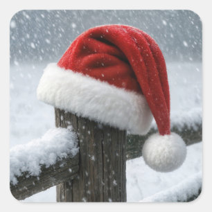 Weihnachtsmannmütze auf einem schneebedeckten Zaun Quadratischer Aufkleber