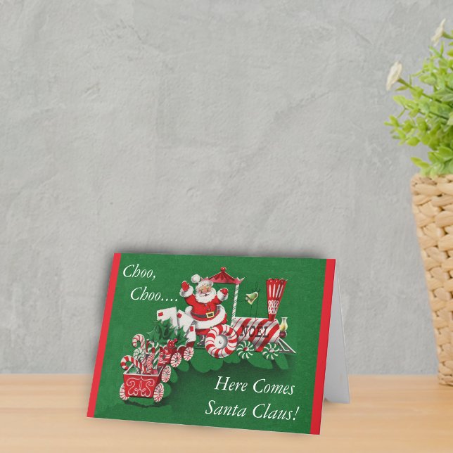Weihnachtszug Feiertagskarte (Santa riding peppermint candy train with letters on a greem Merry Christmas Here comes Santa Card.)