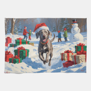 Weimaraner läuft im Schnee mit Weihnachtsmütze Geschirrtuch