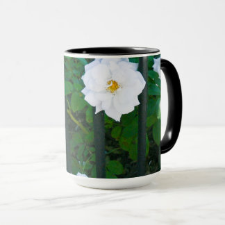 Weiße Blume, die durch den Zaun sprießt Tasse