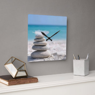 Weiße Feder auf einem Strandsteinmann Quadratische Wanduhr