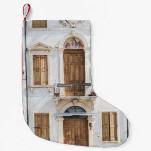 WEISSES, KONKRETES GEBÄUDE MIT HOLZTÜREN UND WIND KLEINER WEIHNACHTSSTRUMPF