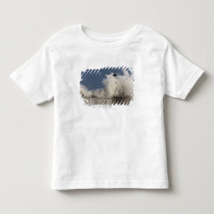 Wellen, die oben gegen einen Leuchtturm Kleinkind T-shirt