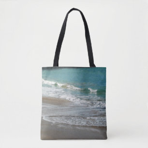 Wellen, die sich am türkisblauen Meer am Strand sa Tasche