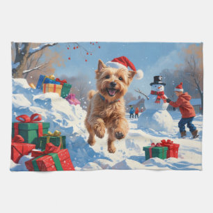 Wheaten Terrier läuft im Schnee mit Weihnachtsmütz Geschirrtuch
