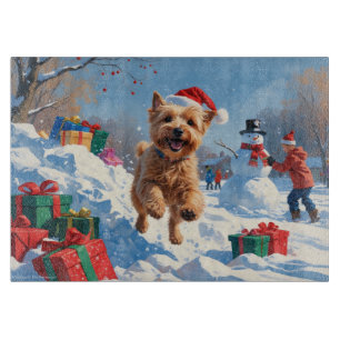Wheaten Terrier läuft im Schnee mit Weihnachtsmütz Schneidebrett