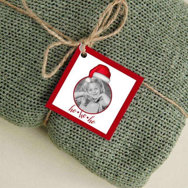 Whimsical Red Painted Weihnachtsmannmütze Geschenkanhänger (Personalized Christmas gift tag with photo and Santa hat design tied to wrapped holiday gift.)