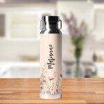 Wildblumen peach beige individuelle Name Skript Trinkflasche<br><div class="desc">Ein pfirsichfarbener Hintergrund. Die Wildblumen sind in Beige,  Creme und Rosa gehalten. Personalisieren Sie Ihren Namen und fügen Sie ihn hinzu. Schwarzes handgeschriebenes Stilskript.</div>