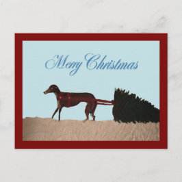 Windhund zieht einen Weihnachtsbaum durch den Schn Postkarte