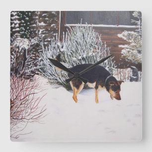 Winter snow scene with cute black and tan dog quadratische wanduhr