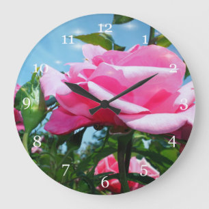 Wunderschöne rosa Rose am blauen Himmel. Florale F Große Wanduhr