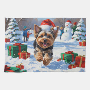 Yorkipoo läuft im Schnee mit Weihnachtshut Geschirrtuch