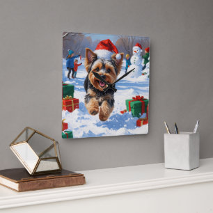 Yorkipoo läuft im Schnee mit Weihnachtsmütze Quadratische Wanduhr
