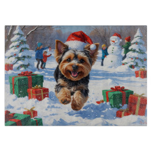 Yorkipoo läuft im Schnee mit Weihnachtsmütze Schneidebrett