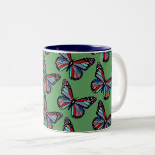 Ziemlich verzierte bunte Schmetterlinge auf Grün Zweifarbige Tasse