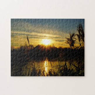 Zonsondergang bij een meertje met rietpluimen.