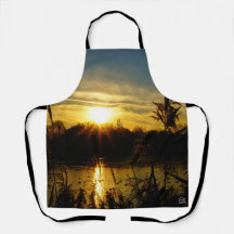 Zonsondergang bij een meertje met rietpluimen.
