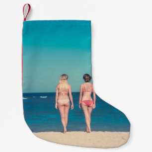 ZWEI FRAUEN, DIE KÜRZLICH BIKINI STEHEND TRAGEN KLEINER WEIHNACHTSSTRUMPF