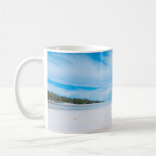 Zwei Frauen liegen auf weißem Sand und liegen dire Kaffeetasse