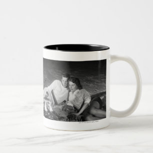 Zwei Paare auf dem Strand, der um Lagerfeuer sitzt Zweifarbige Tasse