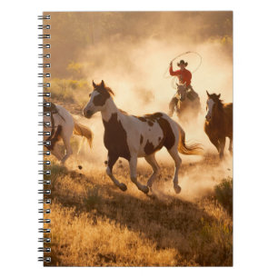 Zwei westliche Cowboys reiten Pferde und werfen wi Notizblock